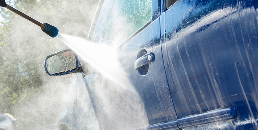 En högtryckstvätt som tvättar en blå bil.