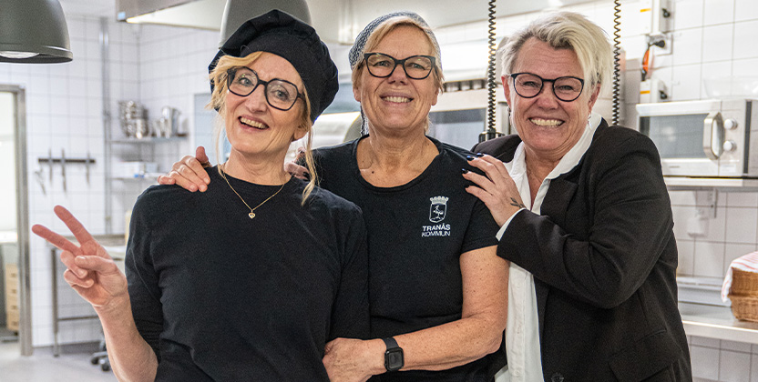 Tre personer i ett skolkök som skrattar och håller om varnadra.