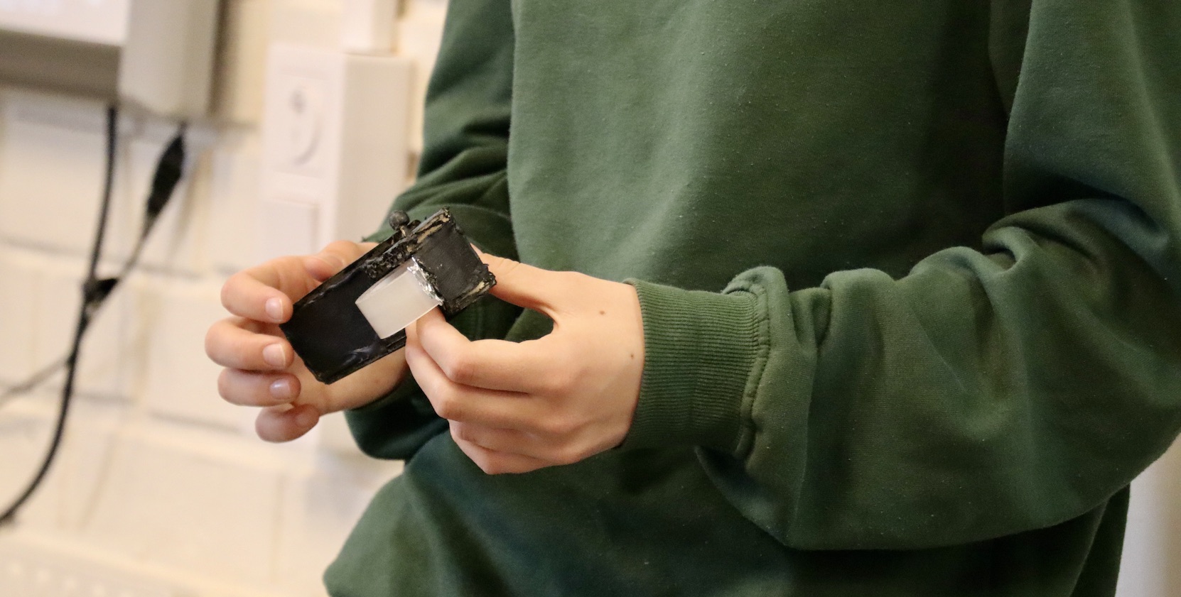 En elev i 15-årsåldern håller i en prototyp av en tejprulle som ska göra det enklare att tejpa rakt och hållbart. 