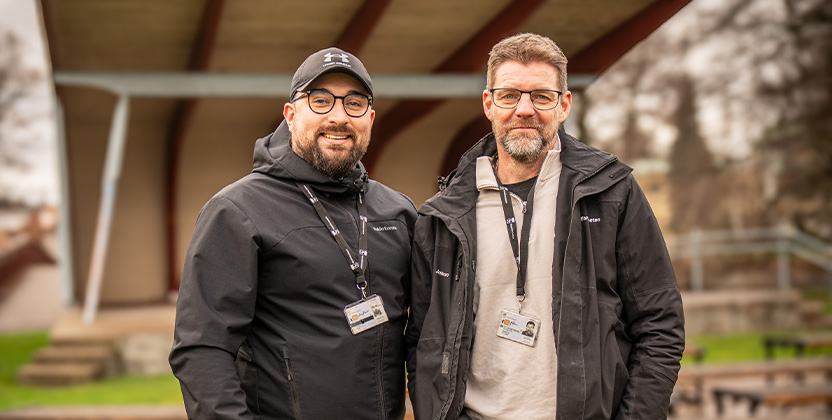 Två personer som kollar in i kameran och ler.