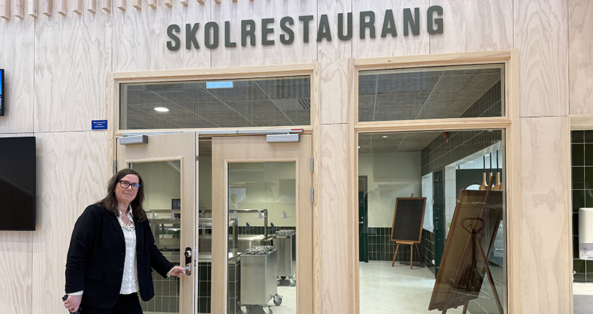 Kvinna öppnar dörren in till en skolrestaurang.